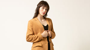 Woman wearing a tan blazer against a white background